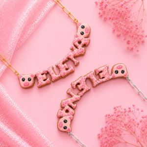 Collares personalizados de cerdito kawaii con nombres decorados en rosa, uno con cadena dorada y otro con cadena plateada.