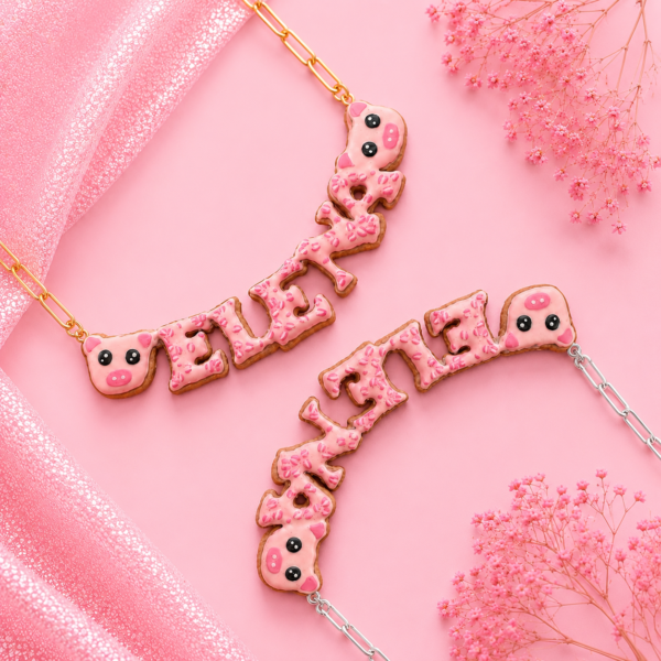 Collares personalizados de cerdito kawaii con nombres decorados en rosa, uno con cadena dorada y otro con cadena plateada.