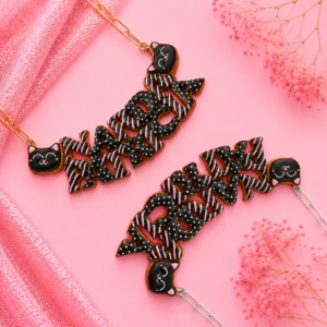 Collares personalizados de gatito negro sonriente kawaii con nombres decorados, uno con cadena dorada y otro con cadena plateada.